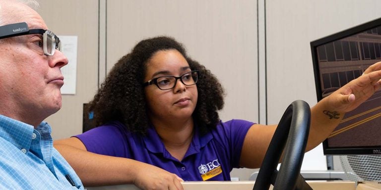 An ECU occupational therapy student works with a participant in the driving simulator in the College of Allied Health Sciences in 2018. (Photo taken pre-COVID-19 by Cliff Hollis)
