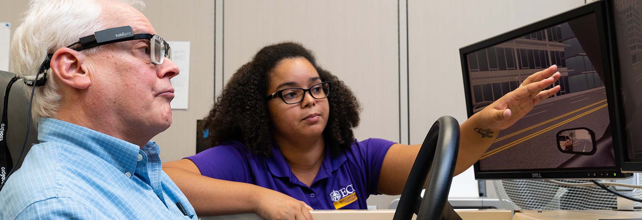 An ECU occupational therapy student works with a participant in the driving simulator in the College of Allied Health Sciences in 2018. (Photo taken pre-COVID-19 by Cliff Hollis)