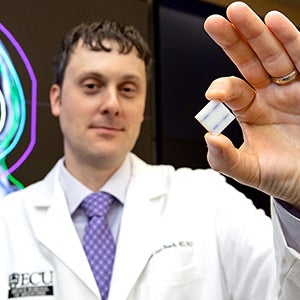 Dr. Matthew Sean Peach, an assistant professor in the Department of Radiation Oncology at ECU’s Brody School of Medicine, holds a Gammatile used to treat brain tumors. 