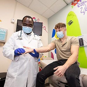 Dr. Beng Fuh examines the hand of Luke Haithcock, who was diagnosed at 15 years old with a rare cancer on the median nerve in his hand. Haithcock is now in remission.