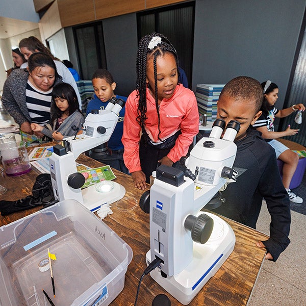 Children use a microscope during the Earth Day Expo at the Life Sciences and Biotechnology Building. 