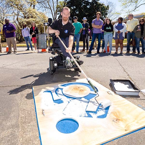 ECU student Brendon Hildreth paints an updated, more active accessible icon on main campus. 