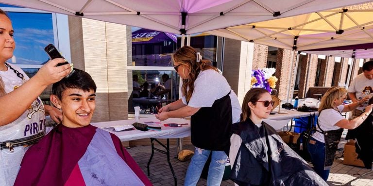 A volunteer cuts hair at ECU's Pirates Vs. Cancer event.