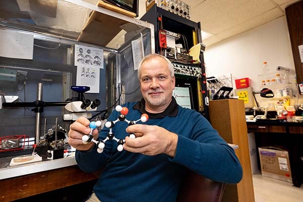 Dr. Stefan Clemens holds a chemical model in his office.