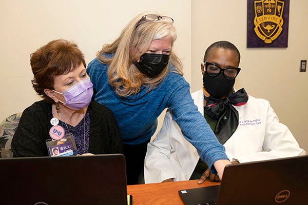 Dr. Courtney Caiola, center, works with Dr. Donna Roberson, left, faculty in the ECU College of Nursing, and registered nurse Grace Wilkins, of the ECU Adult Specialty Care Clinic.