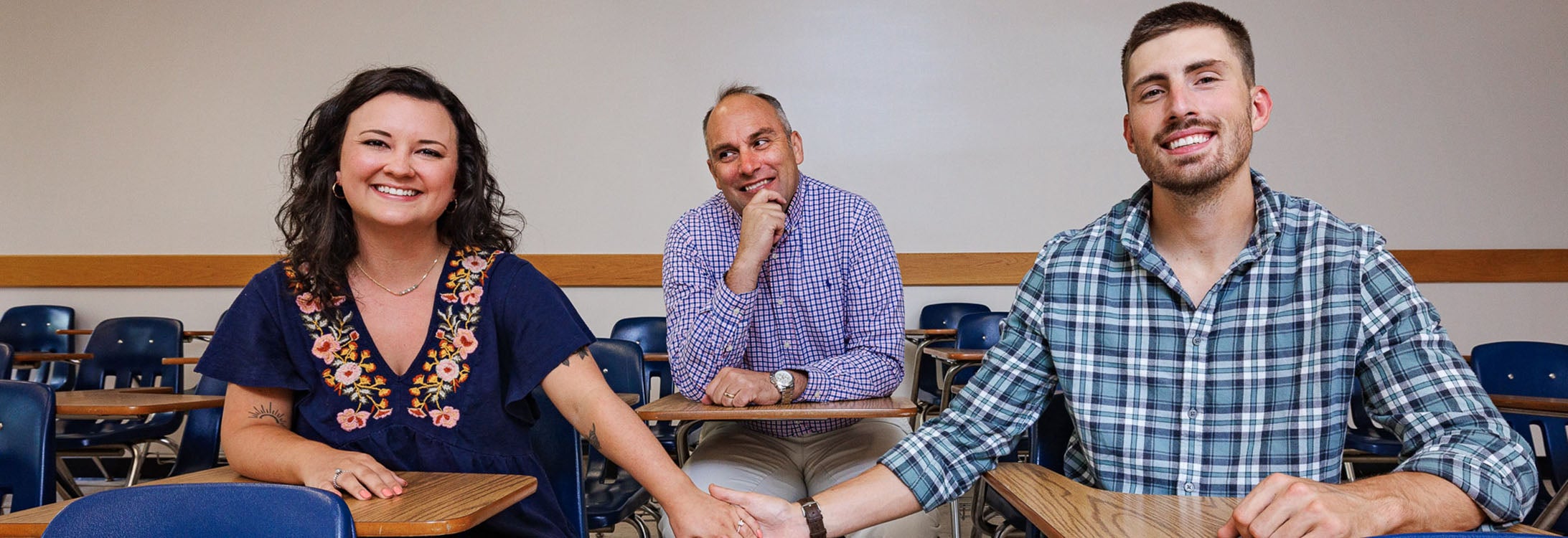 Dr. Damon Rappleyea looks on in the background as engaged couple Chloe Ament, left, and Nick McNeill pose together.