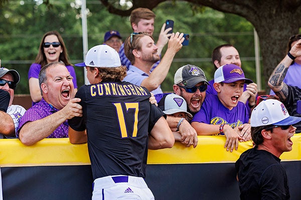 ECU fans celebrate with baseball players after defeating Coastal Carolina.