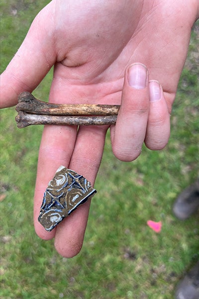 A student displays a piece of Colonial stoneware uncovered during the archaeological dig.