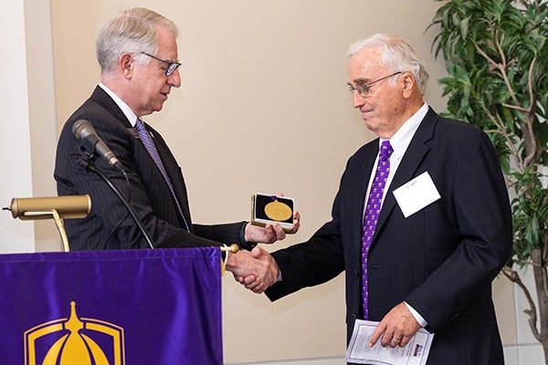 ECU School of Dental Medicine Dean Dr. Greg Chadwick presents Lewis with a commemorative medal during the ceremony honoring Lewis and the inaugural distinguished professor, ECU dental school faculty member Dr. Michael Webb.