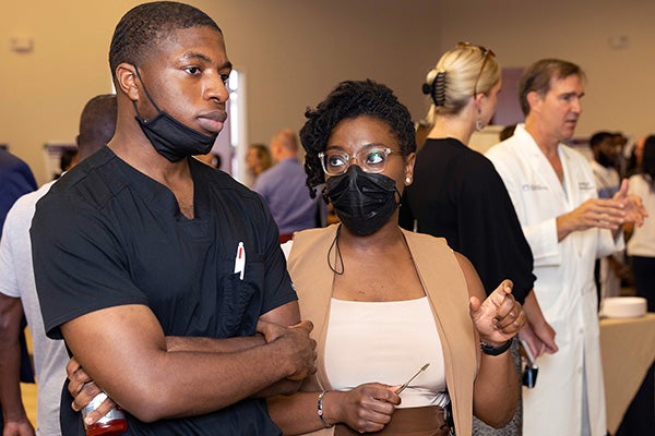 Felicia Branch, right, discusses her project during a poster presentation with Joshua Keku at the 25th Annual Medical Student Scholarship Forum. 