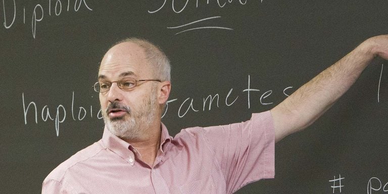 John Stiller points to a chalkboard in class.