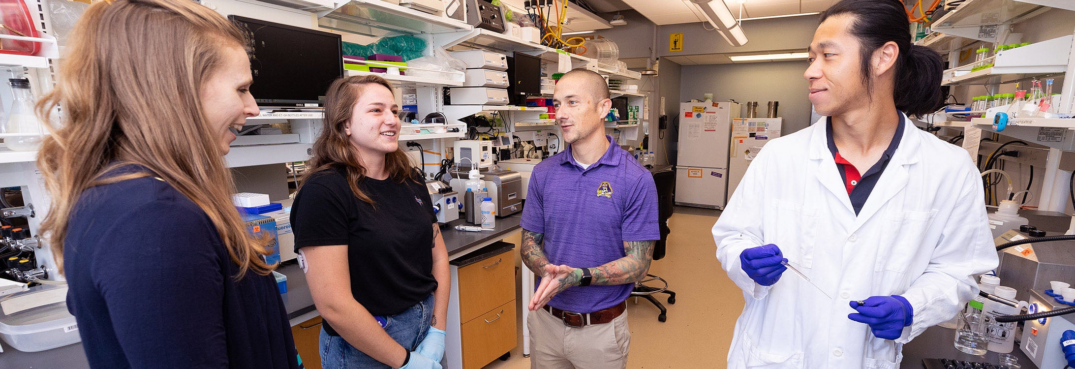 Dr. Kelsey Fisher-Wellman, center, works with students during a lab at the East Carolina Heart Institute. Fisher-Wellman teaches a unique course where instead of final grades, students strive for journal publication.