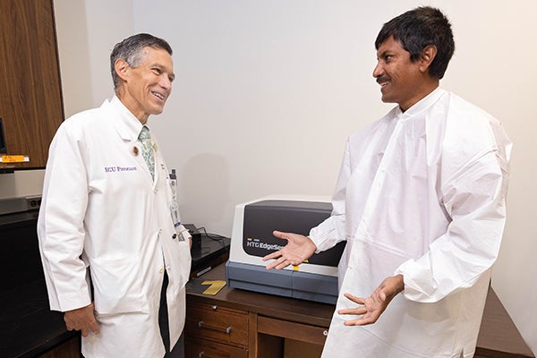 East Carolina University's Dr. Paul Cook and Dr. Shaw Akula discuss microRNA in a lab at the Brody School of Medicine.