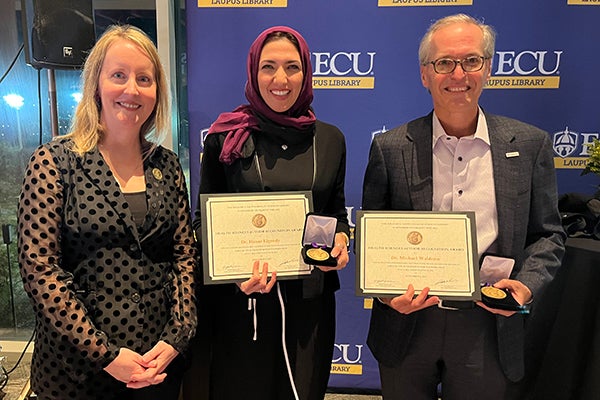 Laupus Library Director Elizabeth Ketterman, left, presents medallions to book authors Dr. Hahan Elgendy from the ECU School of Dental Medicine, center, and Dr. Michael Waldrum, dean of ECU’s Brody School of Medicine and CEO of ECU Health.