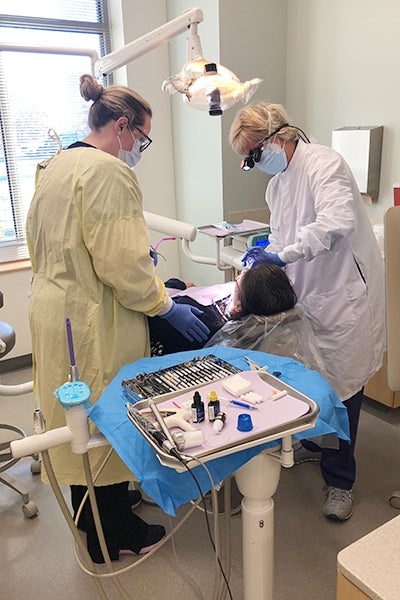 Dr. Dianne Caprio, right, director of the dental school’s community service learning center in Brunswick County, helps provide care during the CSLC’s ECU Smiles for Veterans event in 2021.