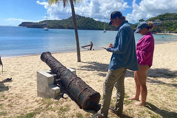 ECU students Dayan Weller and Madison Elsner study a historic cannon at Galleon Bay beach.