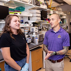 Dr. Kelsey Fisher-Wellman, center, works with students during a lab at the East Carolina Heart Institute. Fisher-Wellman teaches a unique course where instead of final grades, students strive for journal publication.