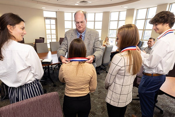 Robert Kulesher, a professor of health services management, presents medals to his case competition team at the College of Allied Health Sciences.