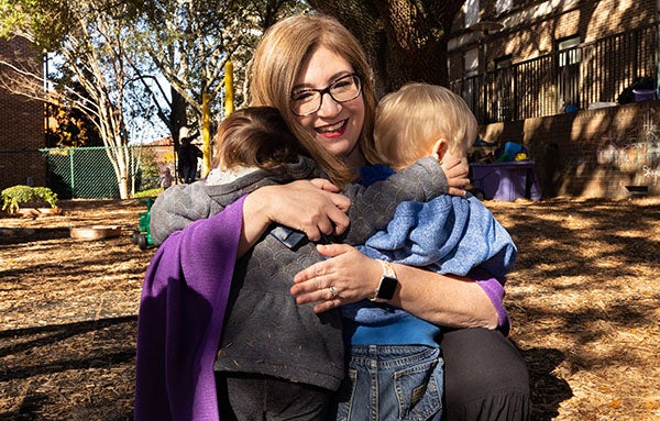 Susannah Berry, interim co-director of ECU’s Nancy W. Darden Child Development Center, receives hugs from children on the playground.