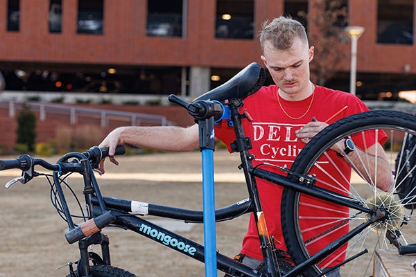 Trent Hohenstreiter works on a bicycle during the Bike Repair Clinic outside the Main Campus Student Center.