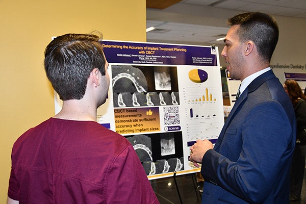 First-year dental student Hunter Jolicoeur, one of the school’s 2022 Summer Research Scholars, shares his research with another student during the school’s annual Celebration of Research and Scholarship.