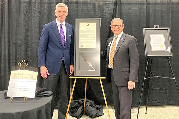 East Carolina University Chancellor Philip Rogers and UNC-Pembroke Chancellor Robin Gary Cummings pose with proclamations honoring Jim Jones, ECU Department of Family Medicine founding chair.