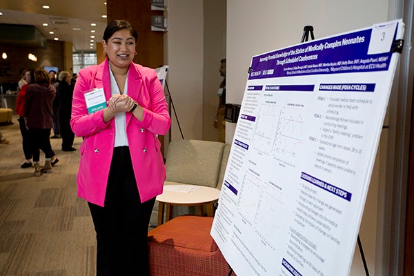Serena Mooney, a third-year student at the Brody School of Medicine, showcases her poster presentation at the Unified Quality Improvement Symposium.