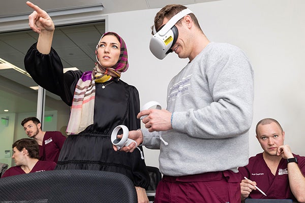 Hanan Elgendy, clinical assistant professor in the ECU School of Dental Medicine, helps first-year student Garren Freeze learn to use the new VR program during class.