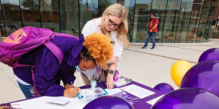 East Carolina University College of Health and Human Performance Director of Outreach Mack Craven, right, helps a student write a thank you letter to a gift donor during last year's Pirate Nation Gives. The annual day of giving returns for the seventh year this Wednesday.