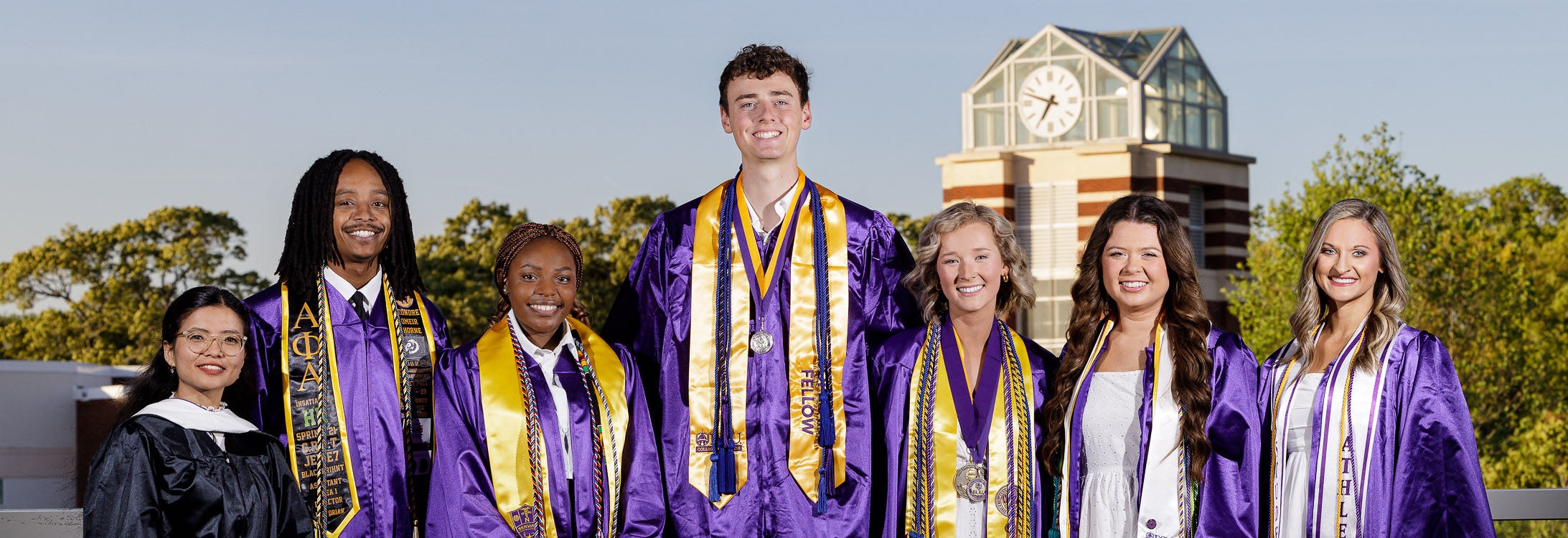 Seven upcoming ECU graduates pose in front of the bell tower.