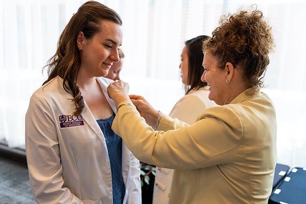 East Carolina University Brody School of Medicine student Jennifer McMains receives a pin from ECU Health Chief Experience Officer Julie Kennedy Oehlert at the Legacy Teachers Celebration April 6.
