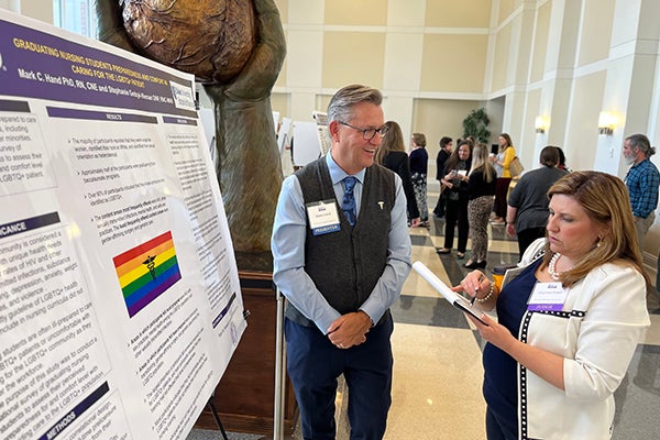 Mark Hand, a nursing professor at the ECU College of Nursing, discusses his research poster with Shannon Powell, also from the CON, during the Brody Medical Education Day. 