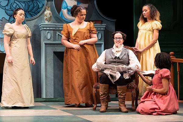 Mr. Bennett, played by junior Sophie Brotemarkle, is surrounded by his daughters during a scene from "Pride and Prejudice."