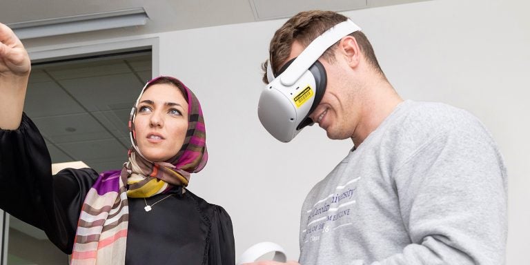 Clinical Assistant Professor Hanan Elgendy helps Garren Freeze learn to use the new VR program during class at the Brody School of Dental Medicine. (ECU Photo by Rhett Butler)