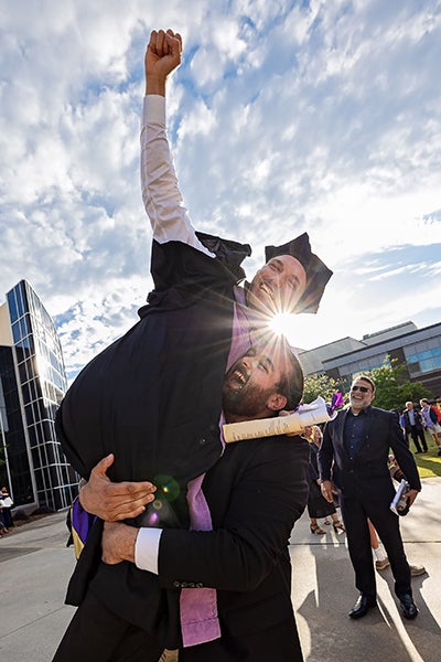 Dental school graduate Omar Taha is lifted in the air by his brother Amir Taha, a first-year dental student, after the 2021 Spring Commencement ceremony.