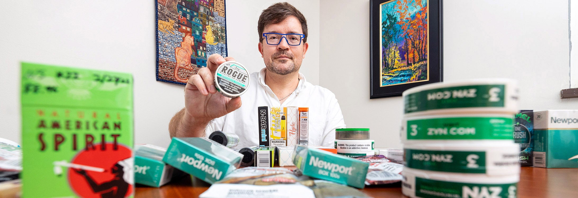 Joseph Lee holds a nicotine pouch product while surrounded by other tobacco products.