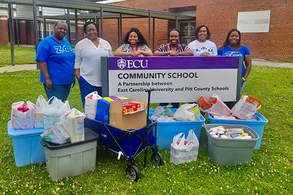 Zeta Phi Beta sorority members Linda McDaniel of Merry Hill and Stephanie Tripp of La Grange, at far left, along with Shakera Robbins of Riegelwood and Deniece Gray of Simpson, far right, present food drive items to ECU Community School counselor Nedra Bruner-Jones and social worker Kristian Backman, in center.