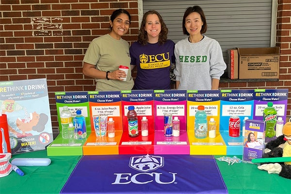 Dental students Tiffany Kurian and Hanna Carter and faculty member Dr. Sukyung Moon man an educational booth at an Exceptional Baseball League event. 
