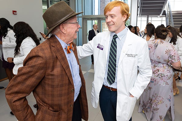 Tom Irons, left, smiles as he stands with his grandson, Thomas Grant Irons III, after receiving his white coat Friday. 