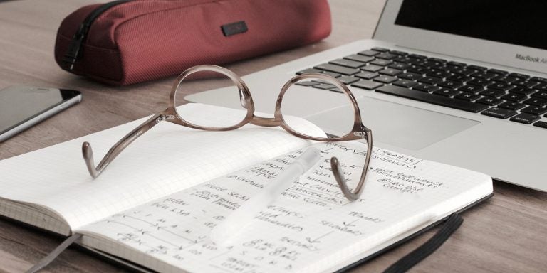 Glasses sitting on papers near a computer