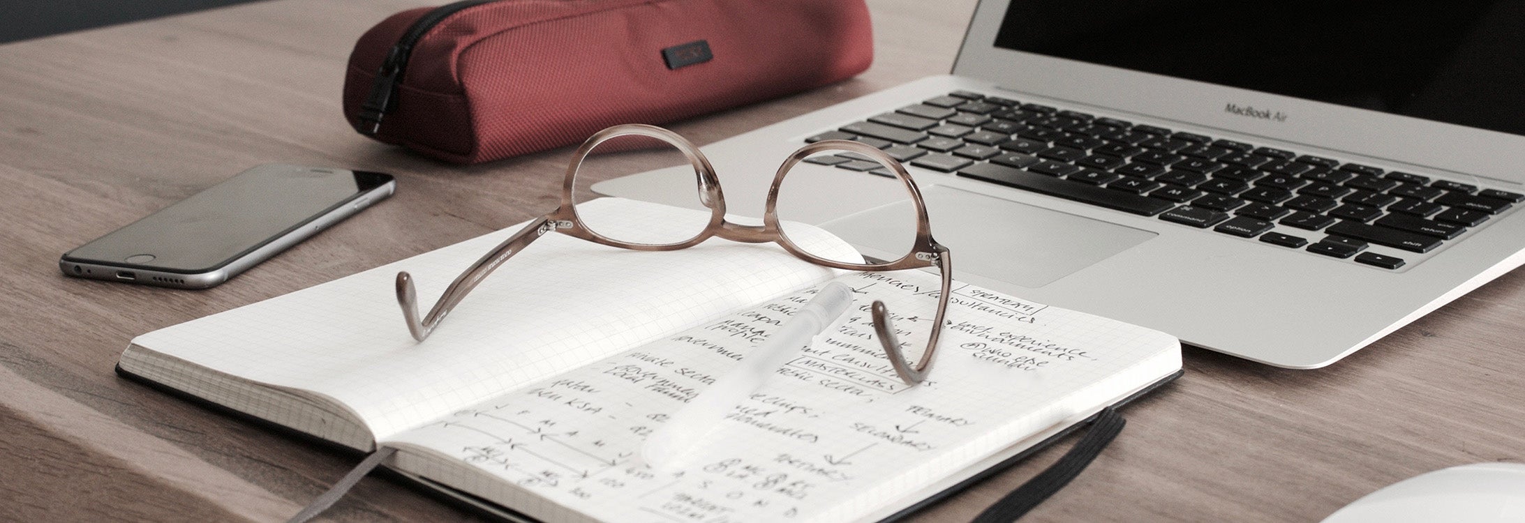 Glasses sitting on papers near a computer