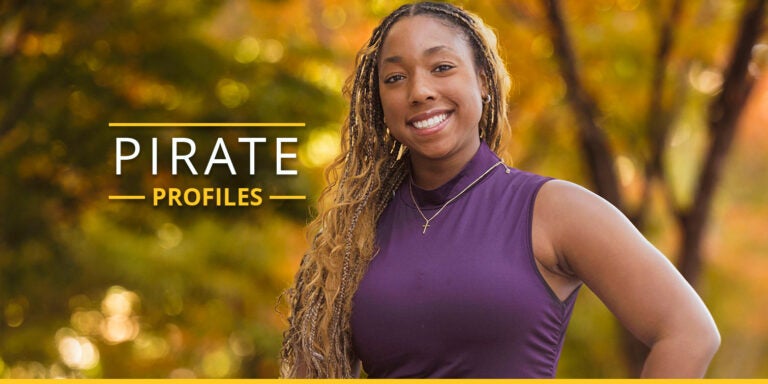 Woman posed in front of trees on campus.