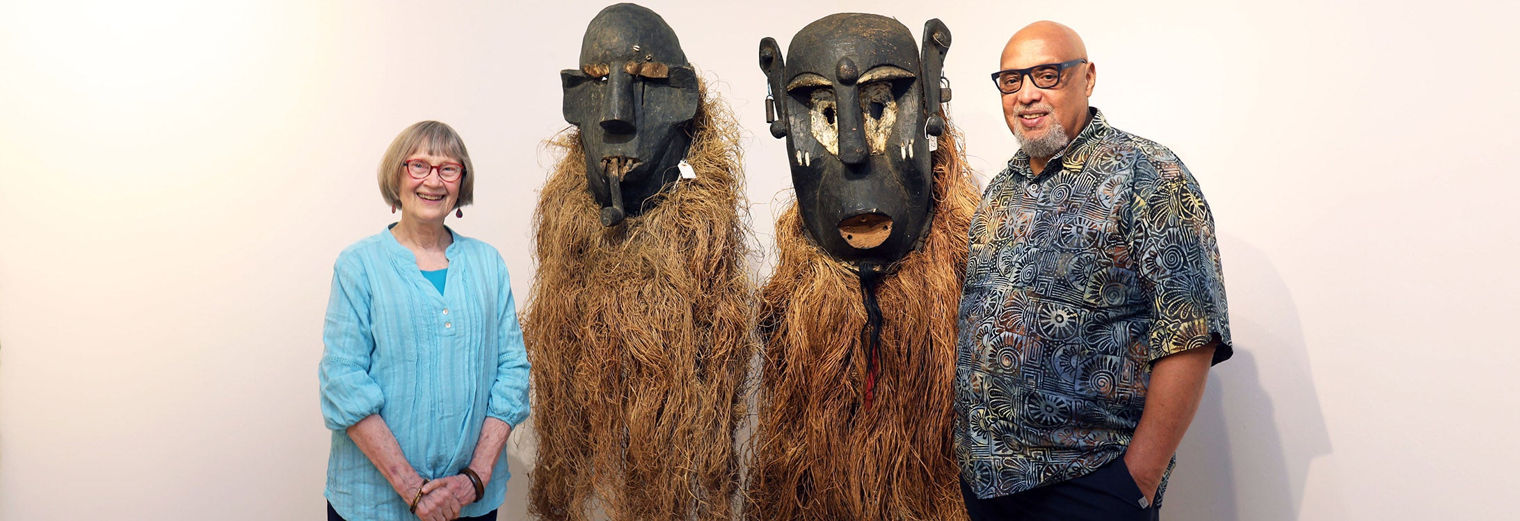 Celeste and Reginald Hodges of Durham stand beside 1950s Gongoli masks they donated to East Carolina University. The masks are part of a collection on exhibit at the Wellington B. Gray Gallery. (ECU photo by Kristen Martin)