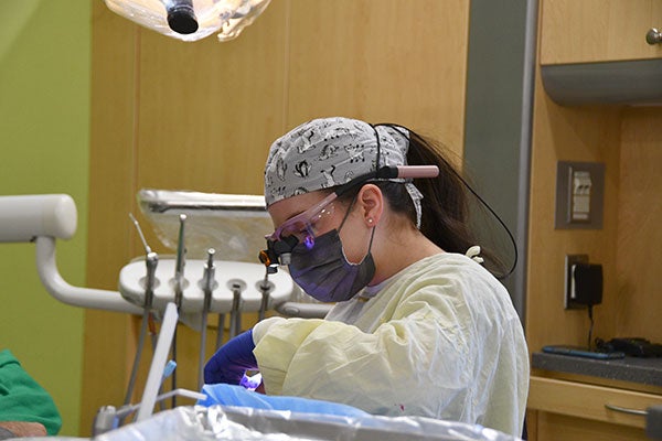 A dental provider in mask and personal protective equipment performs a procedure on a dental patient in an East Carolina University School of Dental Medicine clinic.