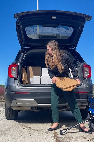 A woman slings an object toward the open back of her sport-utility vehicle.