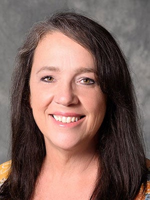 A professional portrait of a woman with dark hair and hazel eye color.