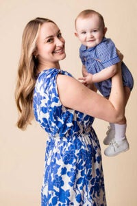 A woman in a blue and white dress holds a baby boy.