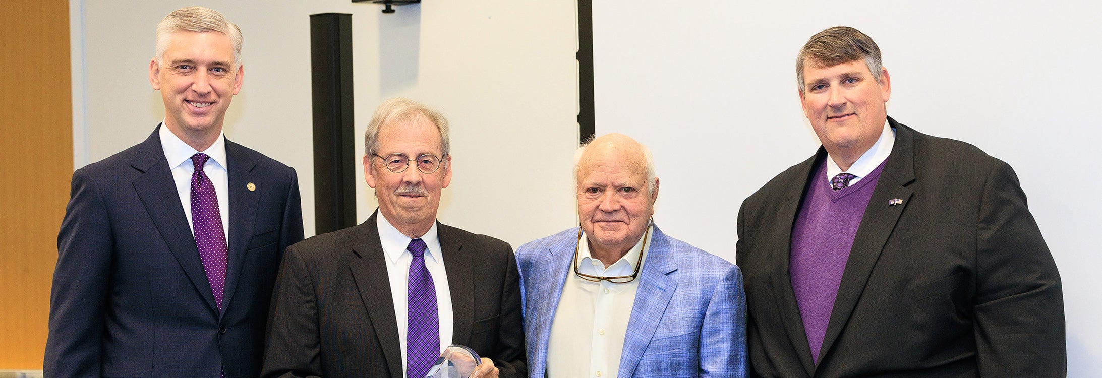 Chancellor Philip Rogers, left, and ECU Board of Trustees chairman Jason Poole, right, honor Jim Westmoreland and Bill Clark, in middle left to right, with the first Trustees Award for Distinction. (Photos by Rhett Butler)