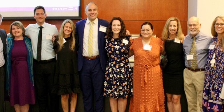 Group of staff and faculty representing ECU marriage and family therapy and medical family therapy stand together in Harvey Hall room.