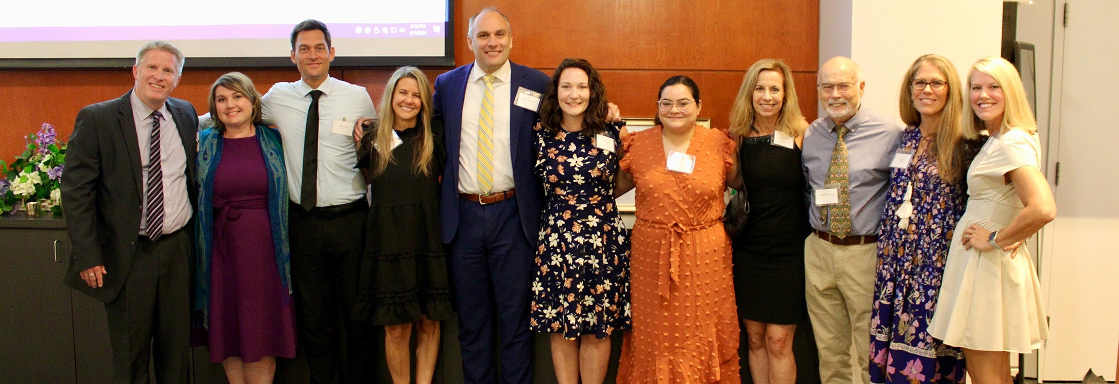 Group of staff and faculty representing ECU marriage and family therapy and medical family therapy stand together in Harvey Hall room.